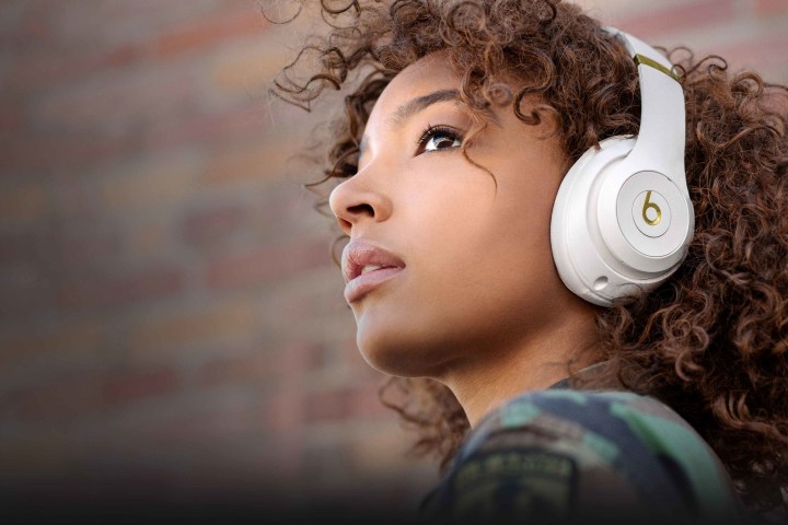 Beats Studio 3 kablosuz kulaklığın beyaz versiyonunu takan bir kız.