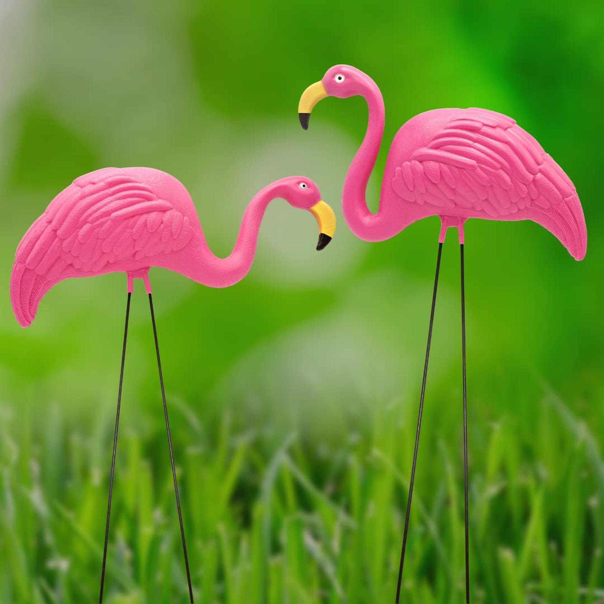 Yeşil çimenlerin üzerinde iki plastik pembe flamingo.