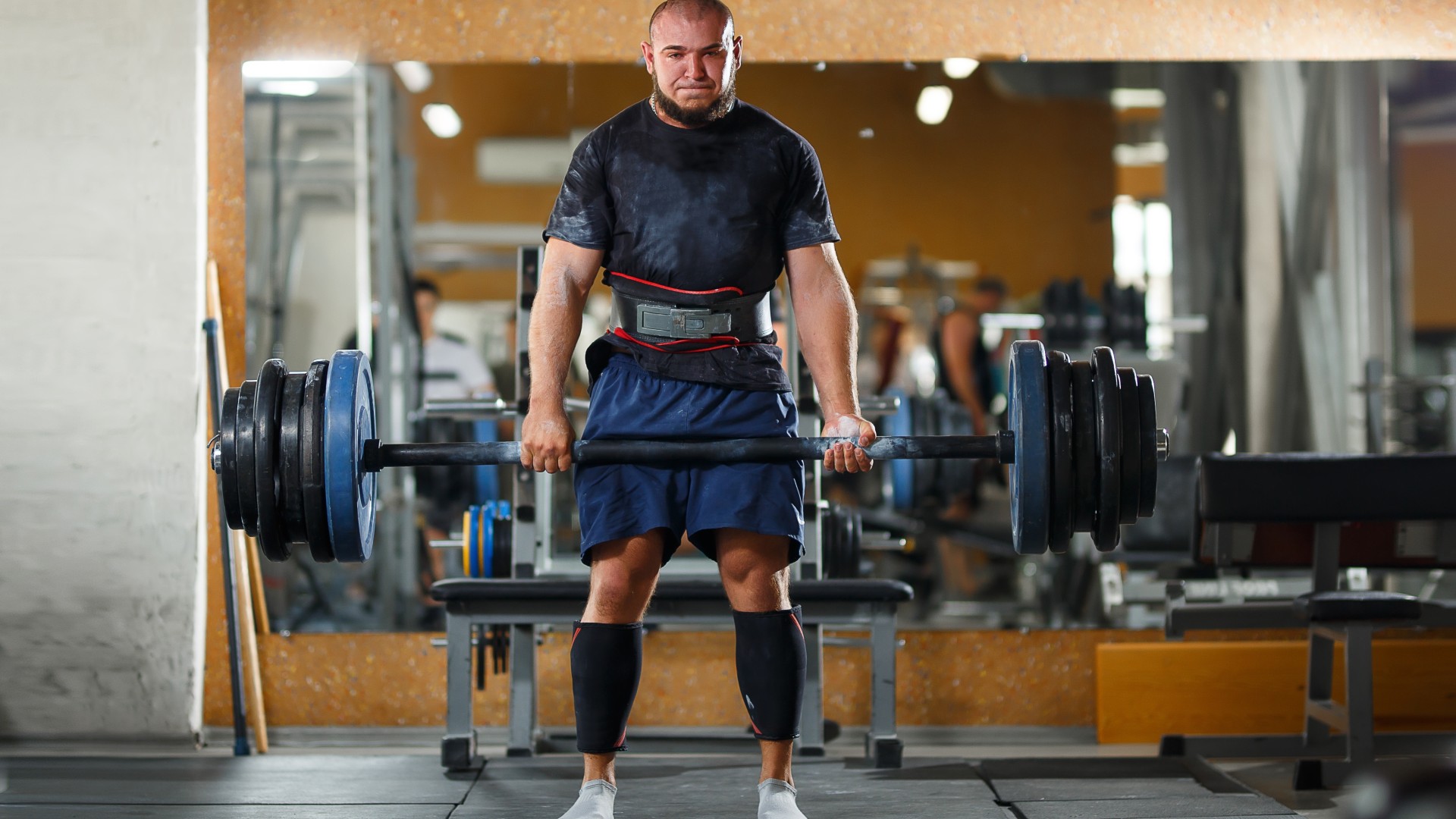 Adam spor salonunda ağır ağırlıkları halter kullanarak kaldırıyor