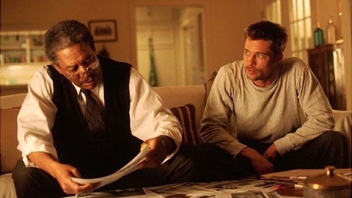 Morgan Freeman ve Brad Pitt, Seven'dan bir sahnede bir kanepede oturup kağıtlara bakıyorlar.