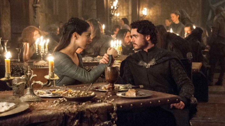 Game of Thrones'ta bir akşam yemeği partisinde Talisa ve Robb Stark rolünde Oona Chaplin ve Richard Madden el ele tutuşuyor.
