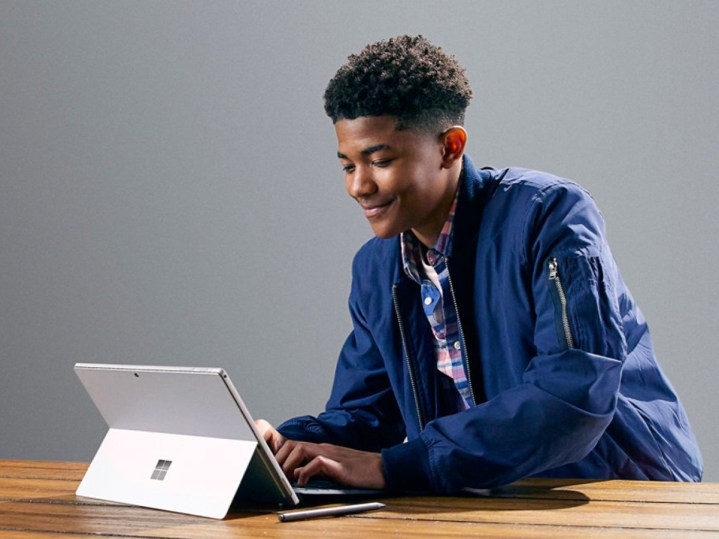Tip Kapağı olan bir masada Microsoft Surface Pro 7 kullanan öğrenci.