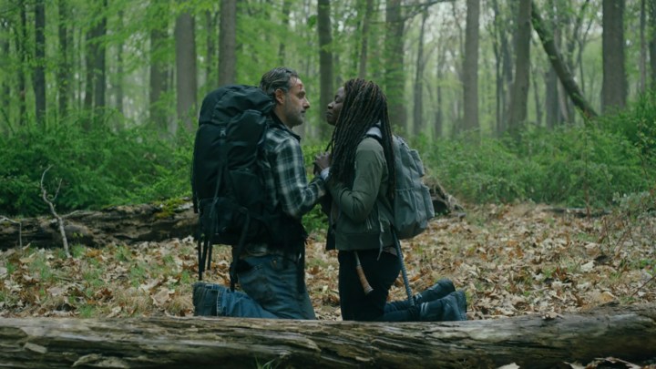 The Walking Dead: The Ones Who Live'da sivil kıyafetli Rick ve Michonne, sırt çantalarıyla bir ormanda diz çöküp birbirlerine bakıyorlar.