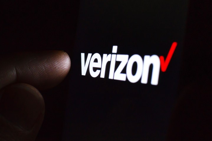 Karanlık bir odada bir akıllı telefon ekranında Verizon logosu ve ona dokunan bir parmak.