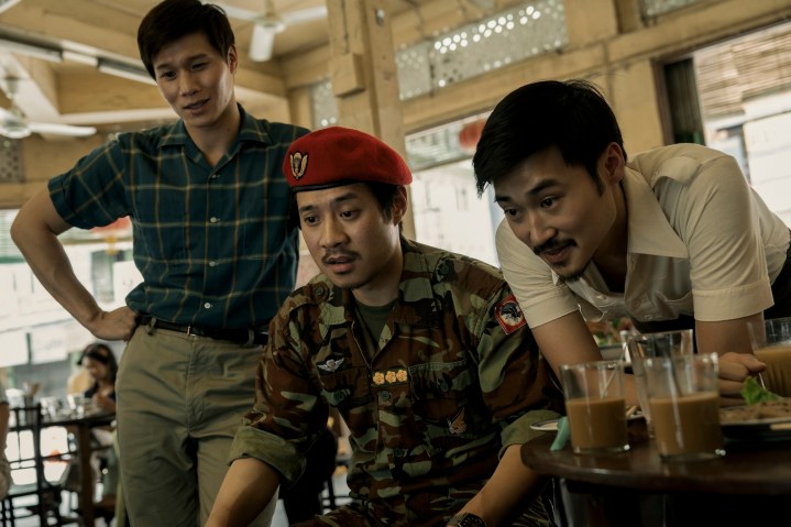 Hoa Xuande, Fred Nguyen Khan ve Duy Nguyen The Sympathizer'da birlikte oturuyor ve ayakta duruyorlar.