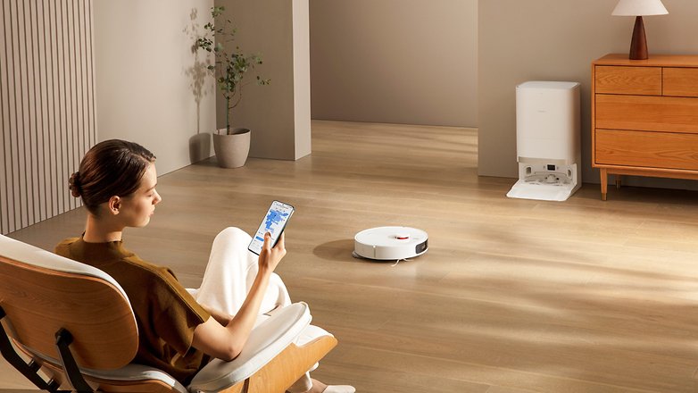 Oturma odasında kullanılan Xiaomi Robot Vacuum X20+, bir kadın tarafından akıllı telefon aracılığıyla kontrol ediliyor