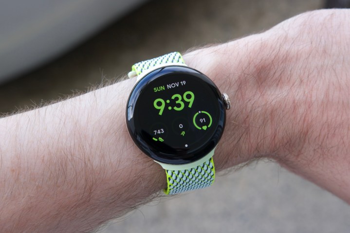 Sarı/yeşil kumaş bantlı Google Pixel Watch 2 takan biri.