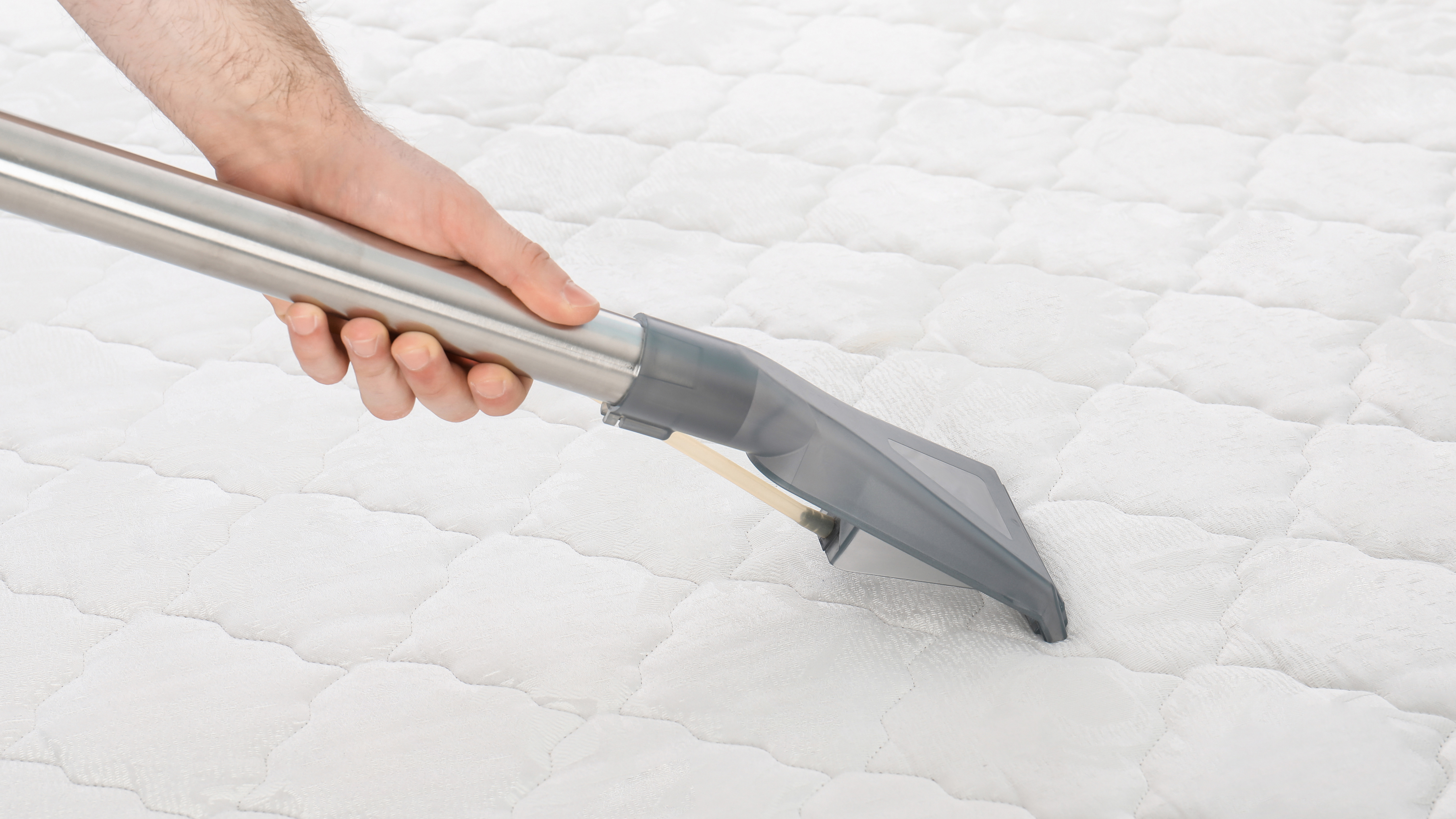 Beyaz bir yatağın yüzeyini elektrikli süpürgeyle temizleme