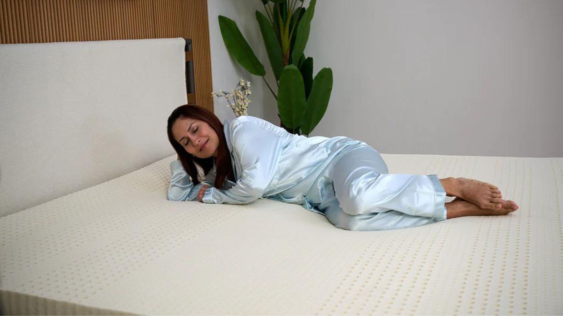 İpeksi mavi pijamalı bir kadın Turmerry lateks yatak örtüsünün üzerinde dinleniyor