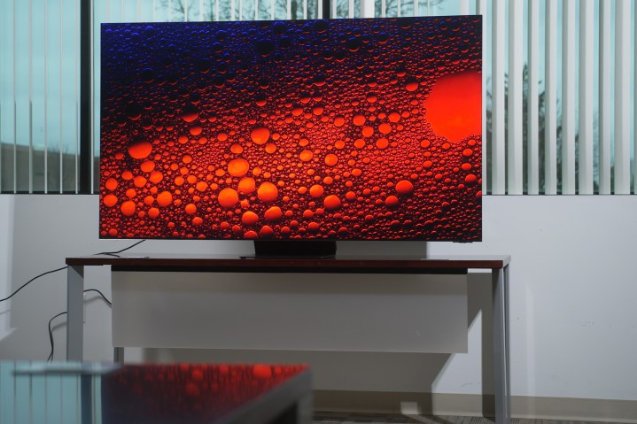 Samsung QN900C QLED 8K Smart Tizen TV, oturma odasındaki bir standın üzerinde duruyor.