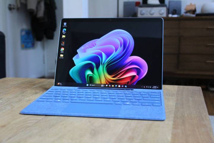 Klavyesi ahşap bir masaya takılı olan Surface Pro 11.