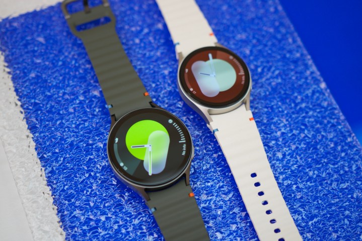 Bir masanın üzerinde yan yana duran iki Samsung Galaxy Watch 7 akıllı saati.