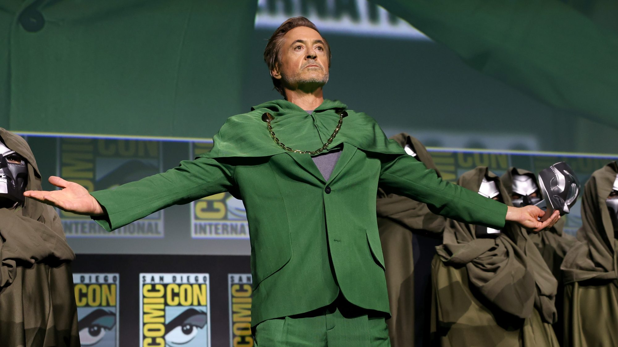 Robert Downey Jr., sağ elinde maske tutan Doktor Doom karakteri kılığında