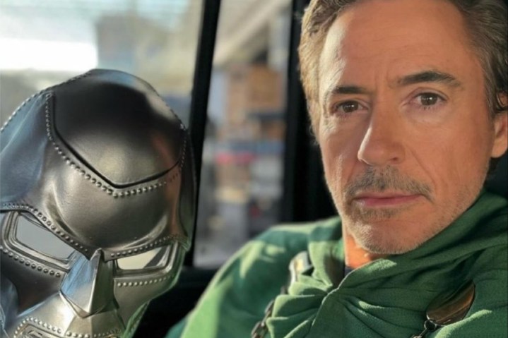 Robert Downey Jr. Doom maskesini tutarken kameraya sırıtıyor.