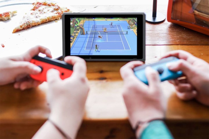 İki kişi masanın üzerinde duran bir Nintendo Switch oynuyor.