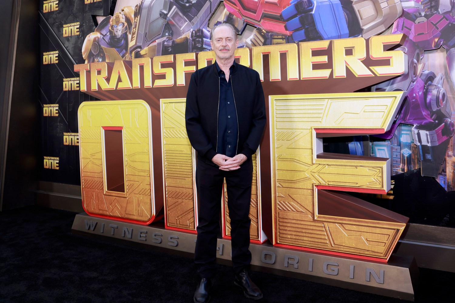 Steve Buscemi, Transformers One fonunun önünde poz veriyor