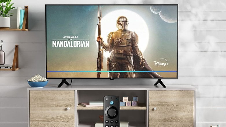 Amazon Fire TV-4, altında uzaktan kumanda bulunan 'Yıldız Savaşları: Mandalorian'ı gösteriyor. Yanındaki kasede patlamış mısır.