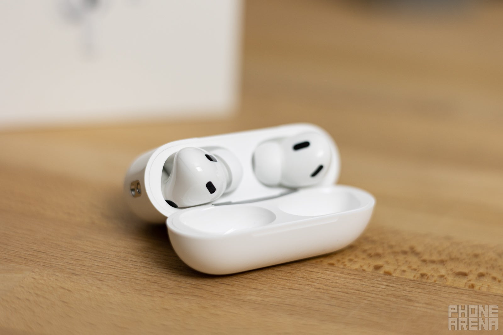 AirPods Pro 2, ahşap bir masanın üzerine yerleştirilmiş şarj kutusunda.