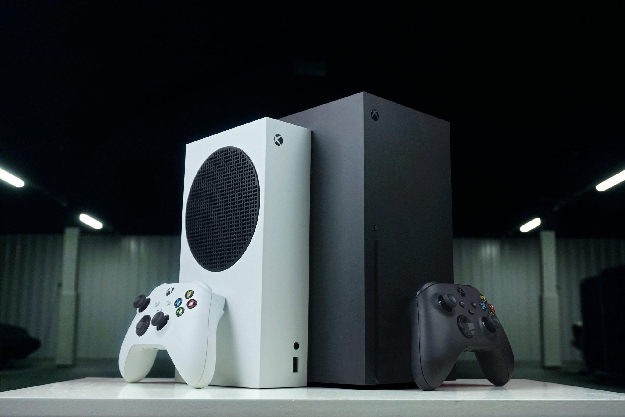 Xbox Series X ve Series S'in Xbox Kablosuz Kontrolcüleriyle yan yana görüntüsü.