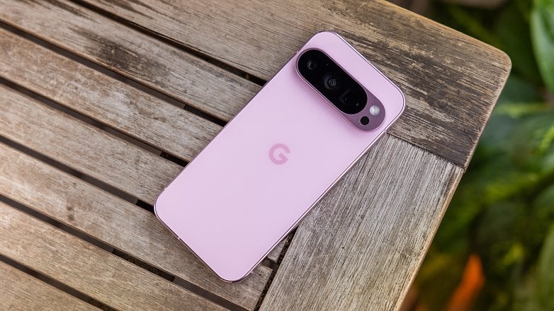 Ahşap bir masanın üzerinde pembe renkli bir Google Pixel 9 Pro akıllı telefon.