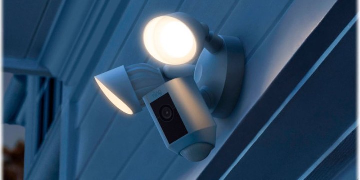 Ring Floodlight Cam Plus bir duvara bağlanarak karanlık bir sahneyi aydınlatıyor.