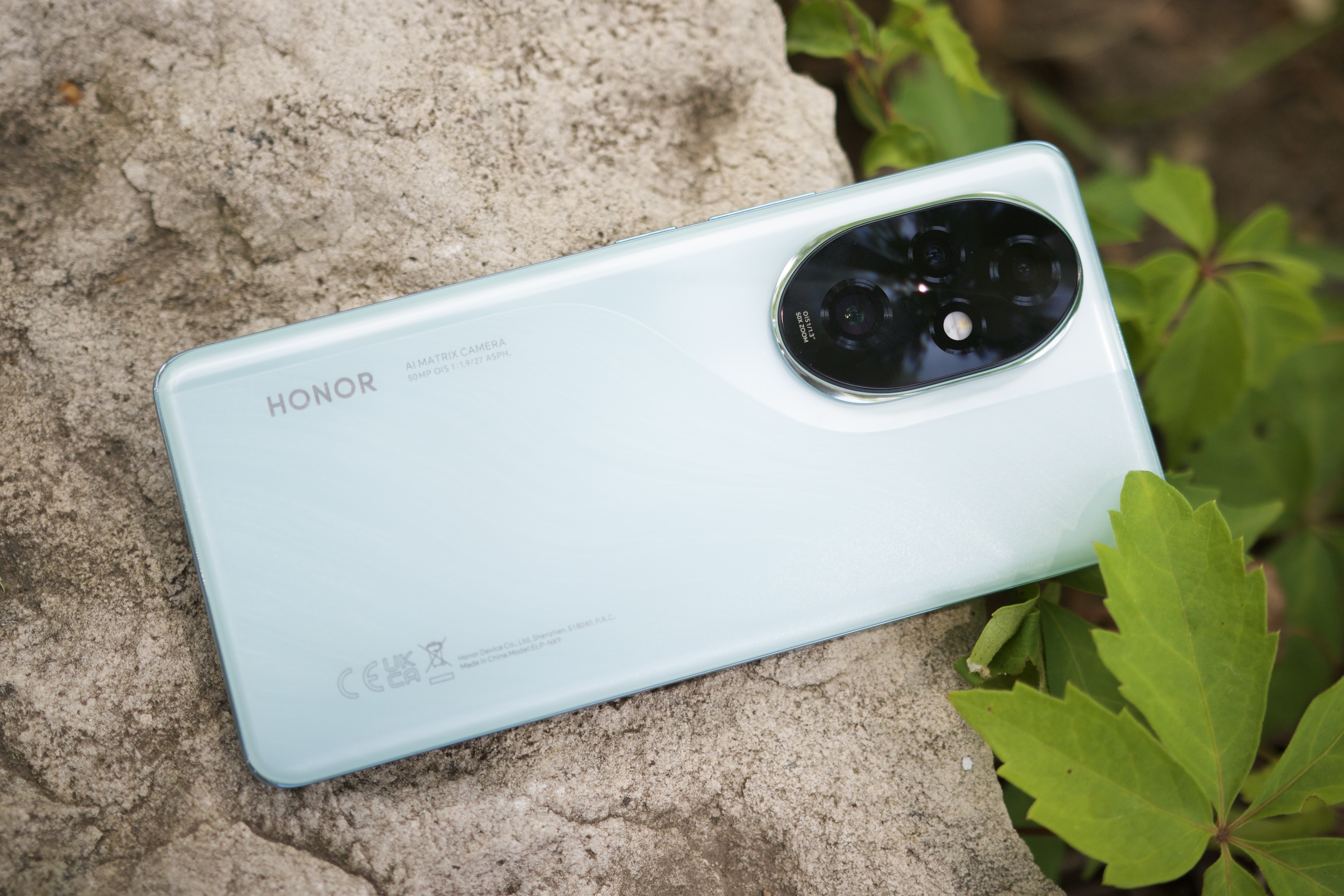 Honor 200 Pro akıllı telefon dışarıda bir kayanın üzerinde yatıyor.