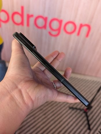 İnce profilli Asus ROG Phone 9'u pembe ekranın önünde tutan bir kişi