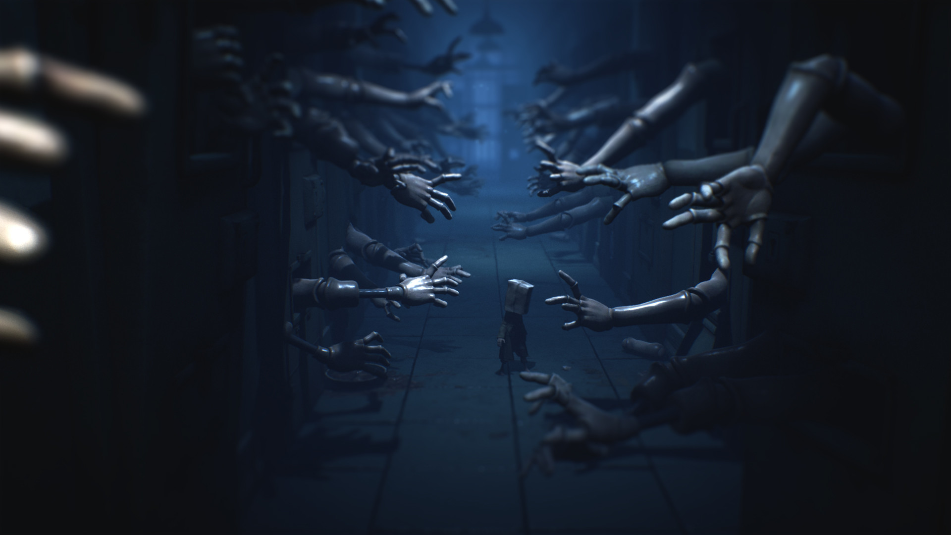 Little Nightmares 2 oynanış görüntüsü, duvarlarının her iki yanından robotik kolların uzandığı karanlık bir koridoru gösteriyor