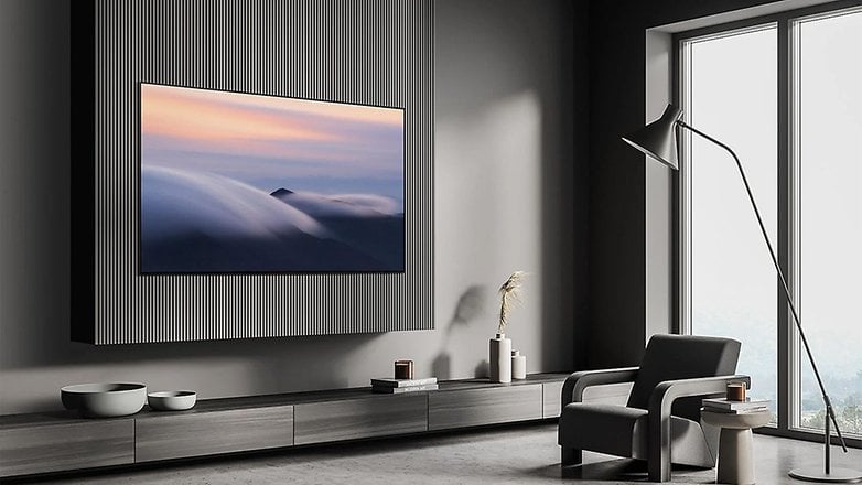 Modern bir oturma odasında şık bir koltuk ile dokulu bir duvara monte edilmiş ince bir Samsung S90D TV.