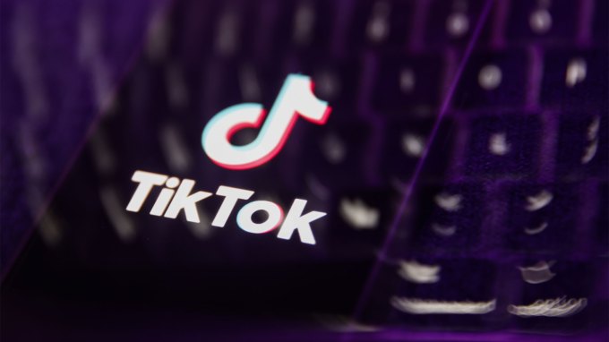 Bu çoklu pozlama çiziminde bir telefon ekranında görüntülenen bir dizüstü bilgisayar klavyesi ve TikTok logosu görülüyor.