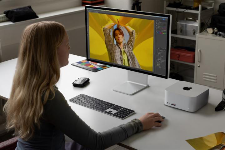 Bir kişi masa başında Apple Mac Studio ve Studio Display monitörü kullanıyor.