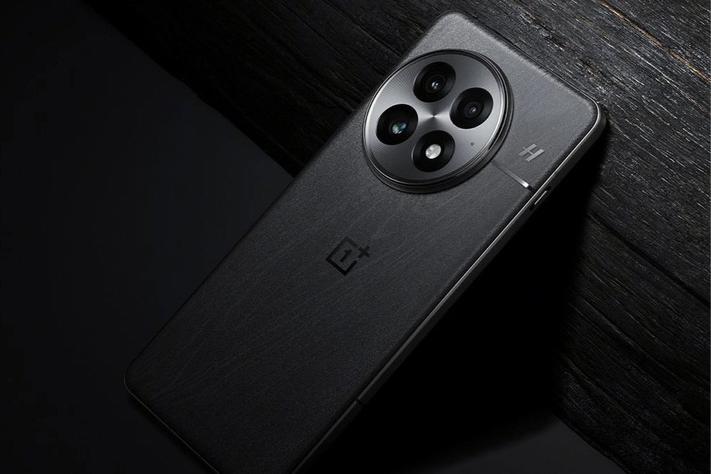 Siyah bir OnePlus 13 akıllı telefon ahşap bir yüzey üzerinde dururken gösteriliyor.