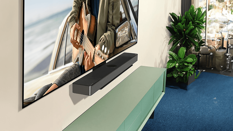 Duvara monte edilmiş ince bir LG C4 OLED Evo TV, altında bir soundbar ve yanında saksı bitkileri.