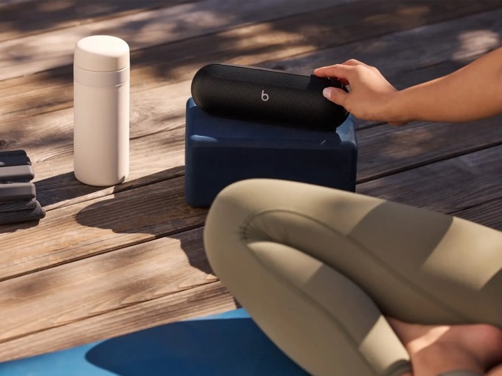 Yoga matındaki bir kadının yanında bir Beats Pill Bluetooth hoparlörü.