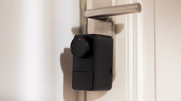 Metal saplı bir kapıya monte edilmiş siyah SwitchBot Lock Pro.