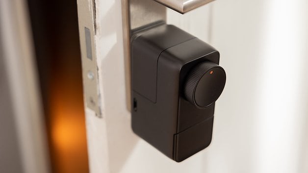 Siyah tasarımlı ve döner düğmeli bir kapıya takılı SwitchBot Lock Pro akıllı kilit.