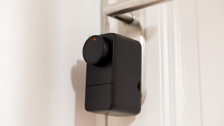 Yuvarlak bir döner düğme ve küçük bir gösterge ile bir kapıya monte edilmiş bir Siyah Switchbot Lock Pro. Yuvarlak bir döner düğme ve küçük bir gösterge ile bir kapıya monte edilmiş bir Siyah Switchbot Lock Pro.