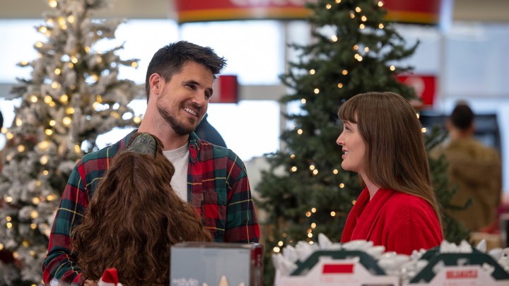 Robbie Amell ve Leighton Meester, bir kutlama mağazasında EXmas filminden bir sahnede birbirlerine bakıyorlar ve gülümsüyorlar.