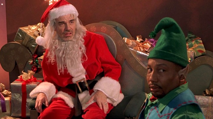 Kötü Noel Baba'da Noel Baba gibi giyinmiş iki adam ve bir elf aynı yöne bakıyor.
