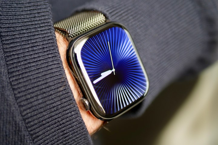 Reflections saat kadranına sahip titanyum Apple Watch Series 10 takan bir kişi.