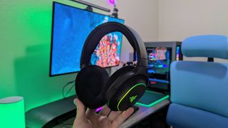 RGB aydınlatması etkinleştirilmiş halde elde tutulan bir Razer Barracuda X Chroma kulaklık.