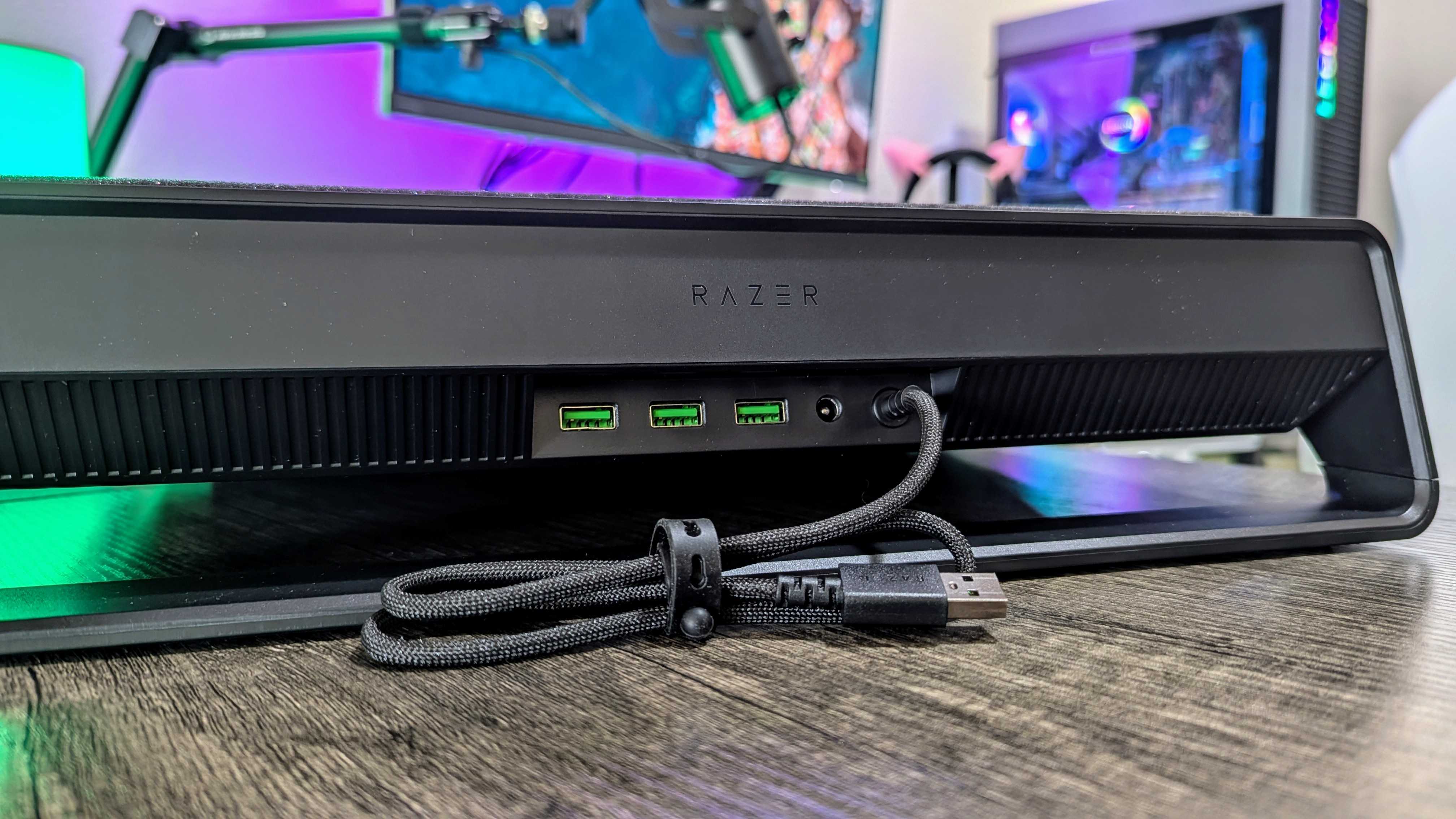 Masanın üzerindeki Razer Dizüstü Bilgisayar Soğutma Pedi, arkadan bakıldığında üç USB Type-A 2.0 bağlantı noktasını, 36W DC güç bağlantı noktasını ve bağlantı kablosunu ortaya çıkarıyor.