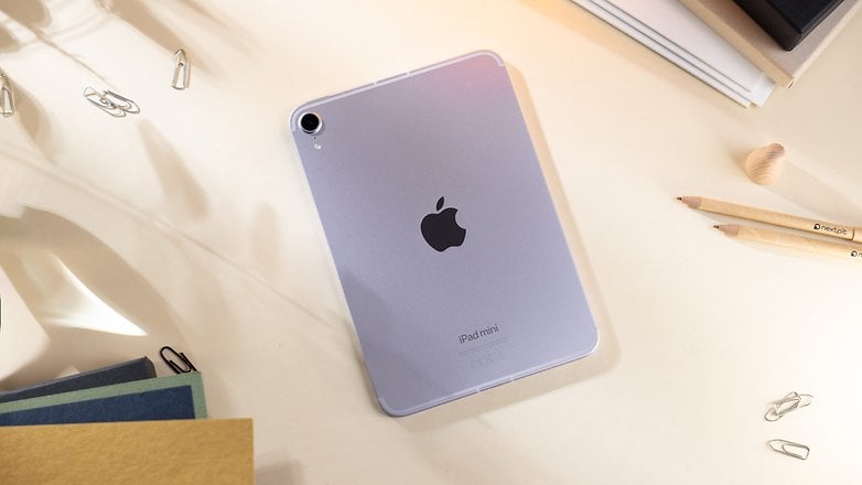 Apple iPad Mini 7, kağıt ve kalemlerle çevrili bir masanın üzerinde logoyla birlikte gösteriliyor.