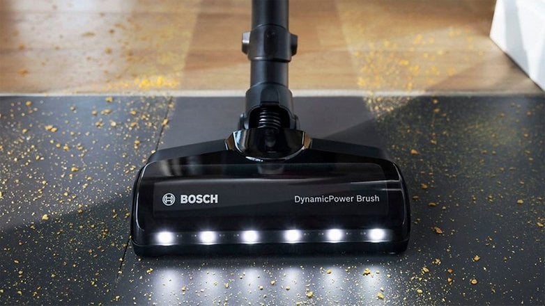 DynamicPower fırçalı Bosch elektrikli süpürge kafası ve dağınık kir içeren bir yüzeyde LED ışıklar.