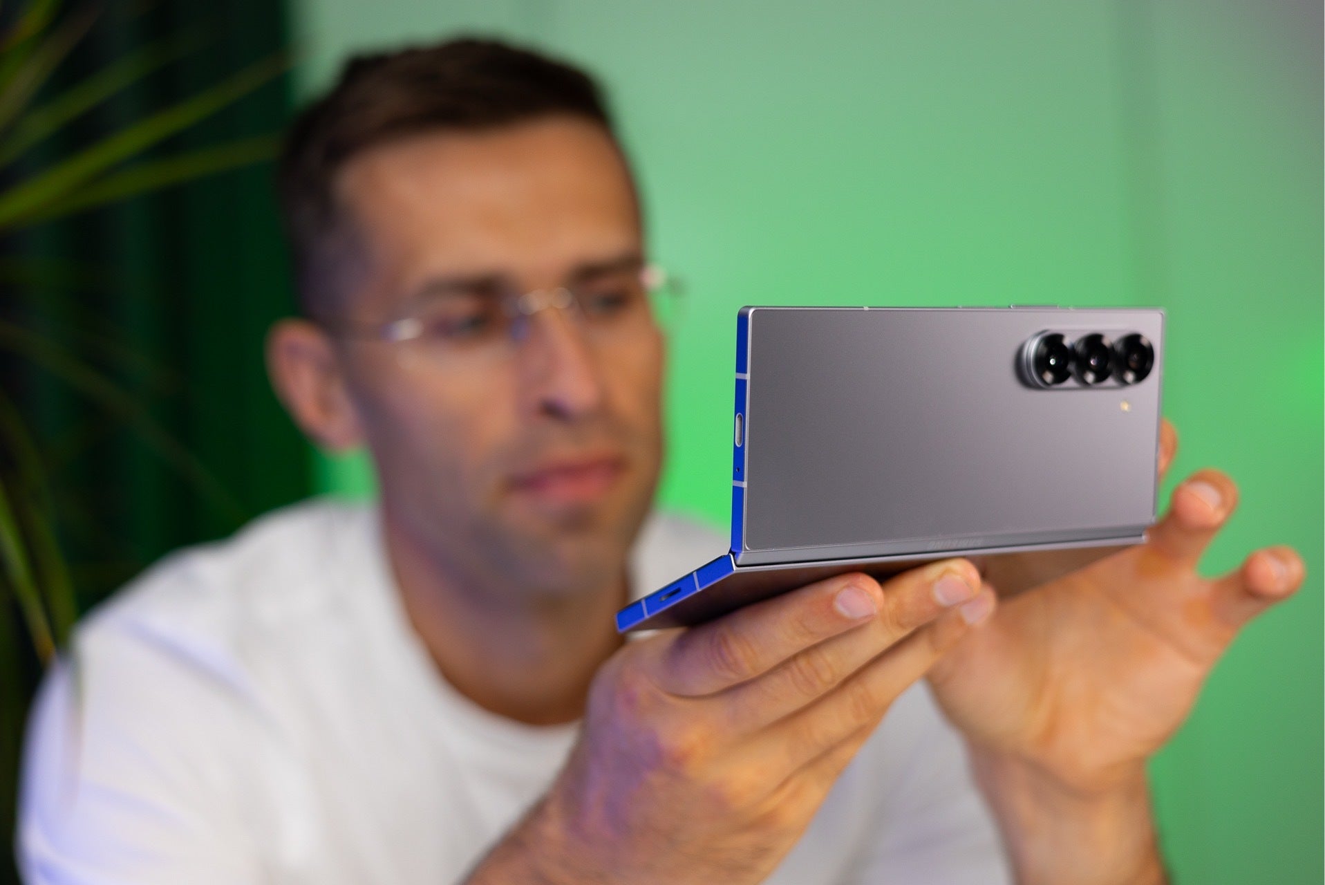 Bir adam arka planda yeşil ekranı olan Samsung Galaxy Z Fold 6'yı sergiliyor