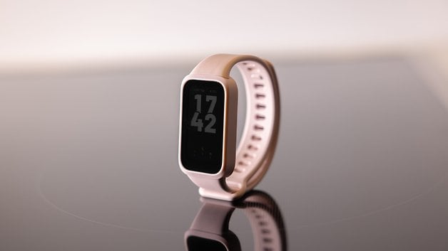 Yansıtıcı bir yüzey üzerinde saat 17:42'de görüntülenen bir Xiaomi Smart Band 9 Active.