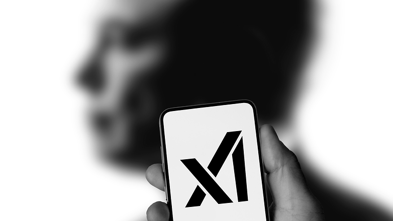 xAI logolu bir akıllı telefonun arkasında bulanık bir Elon Musk