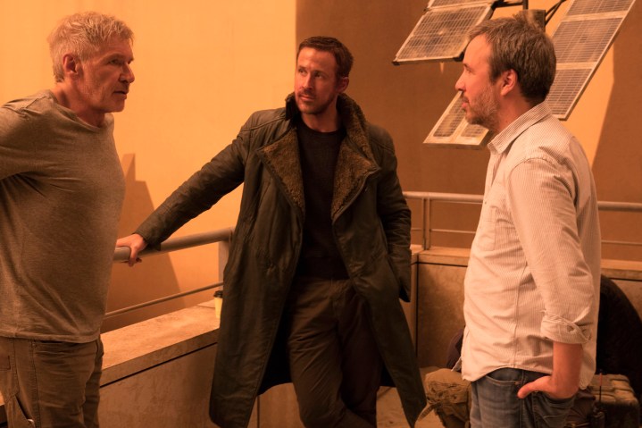 Denis Villeneuve, Blade Runner 2049 setinde Harrison Ford ve Ryan Gosling ile birlikte duruyor.