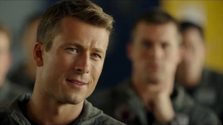 Glen Powell, Top Gun: Maverick'te bakıp sırıtıyor.