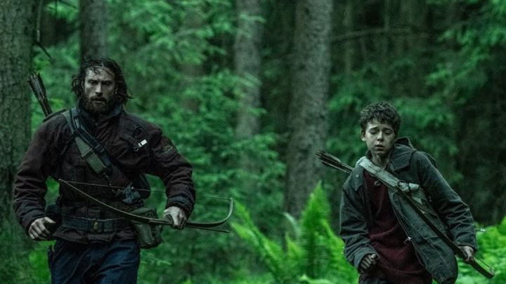28 Yıl Sonra'da bir adam ve bir oğlan ellerinde yaylarla koşuyor.